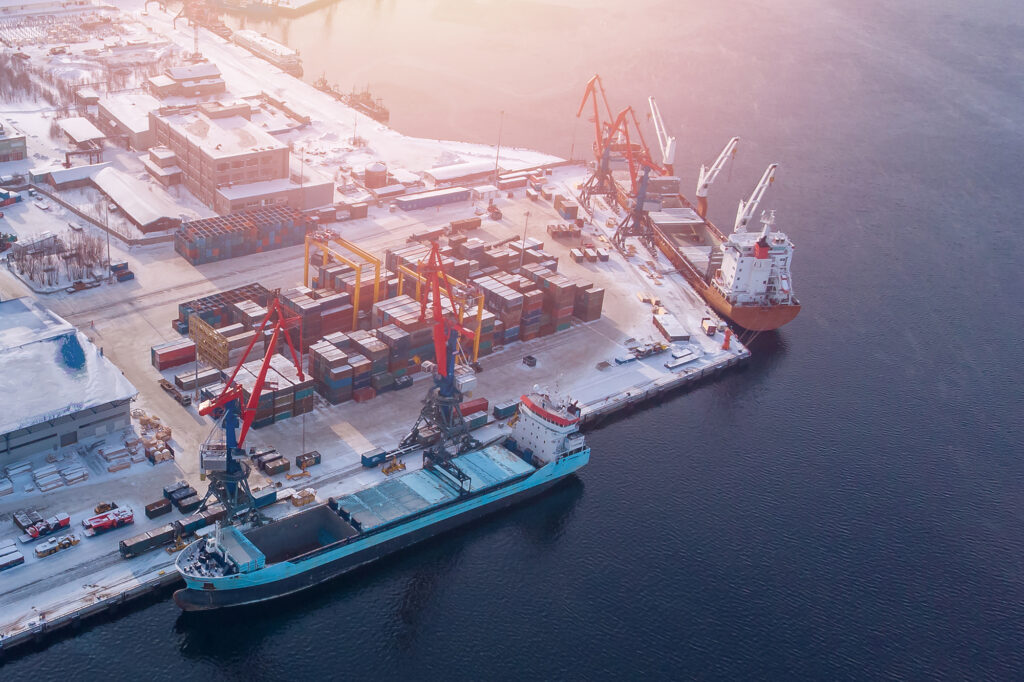 Container cargo ship loading North Arctic port. Concept freight transportation import export and business logistic, aerial view winter