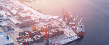 Container cargo ship loading North Arctic port. Concept freight transportation import export and business logistic, aerial view winter