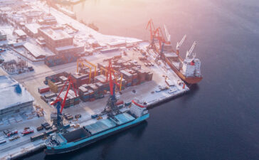 Container cargo ship loading North Arctic port. Concept freight transportation import export and business logistic, aerial view winter
